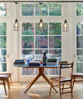 Three Light Plug In Pendant With Hemp Rope And Metal Cage Shades over dining table in bright room with large windows