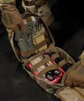Rhino Rescue IFAK trauma kit in tan camo MOLLE pouch, open to reveal C-A-T tourniquet, dressings, shears, and gauze.