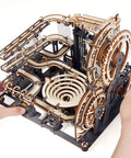 Hands assembling 3D Wooden Marble Run Puzzle Kit For Adults, Mechanical Marble Track Building Set With 294 Pieces, Night City themed.