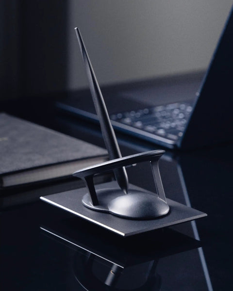 Hoverpen Interstellar Space Black Ballpoint Pen For Desk Aesthetic with elegant stand on dark desk, premium futuristic design.
