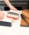 Compact Dustpan And Brush Set With Snap In Design And Bristle Cover cleaning crumbs on countertop near bread