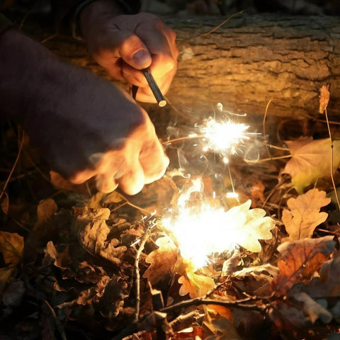 Using 4 Pack Five Sixteenth Inch Ferro Rod Fire Starters With Wood Handles And Multi Tool Striker to ignite leaves outdoors.