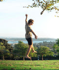 Person balancing on 1 Inch Slackline Kit With Dual Ratchet System 82 Foot Jungle Line Webbing Two Tone Design To Eliminate Twists