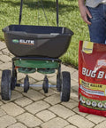 Bag of All In One Lawn Insect Killer next to lawn spreader on pavement, designed to kill ants, fleas, ticks, and more for 3 months