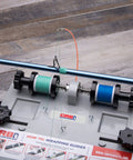Close-up of Compact Hand Wrapper System With Two Spool Thread Tensioner, featuring threaded rod and spring-loaded knobs.