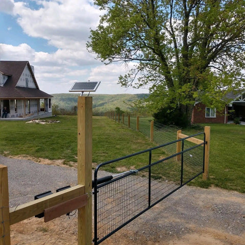 Solar Gate Opener Kit For Driveway Swing Gates Up To 20 Feet And 900 Pounds installed on wire mesh gate in countryside setting