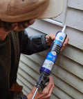 Person applying All Purpose Silicone Caulk Clear 10 Fl Oz Cartridge 12 Pack 100 Percent Waterproof Sealant to exterior siding