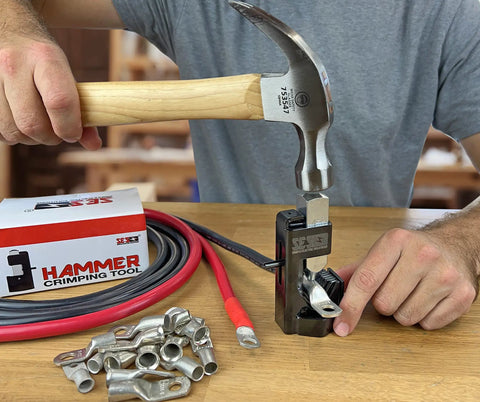 Battery Lug Crimping Tool For 8 AWG Through 4/0 AWG Cables being hammered to crimp automotive wiring lug on a workbench