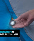 Close-up of Moonlit Rechargeable Micro Lantern for Camping and Hiking clipped to blue tent with carabiner