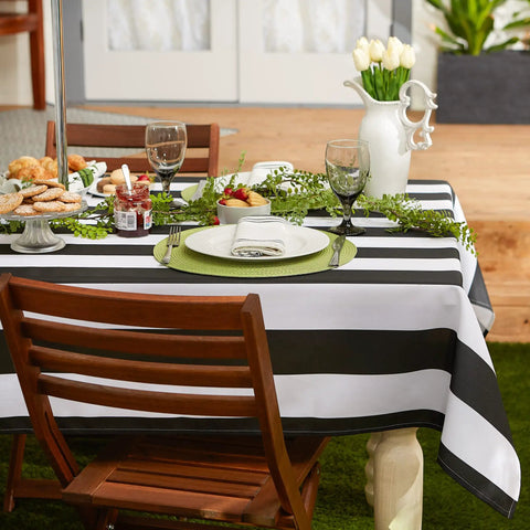 Cabana Stripe Outdoor Zippered Tabletop Cover 60 by 84 Inches Stain Resistant and Waterproof Machine Washable Easy Care for Patio Tables That Seat 6 to 8 Black on wooden outdoor table with white dishes and greenery centerpiece.