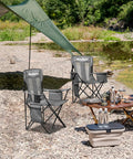 2 Pack Foldable Outdoor Camping Chairs with Built In Cooler Pouch Ultra Comfy Cushioned Seats Mesh Backrest and Cup Holder Pocket in Grey set up by a riverside with picnic equipment.