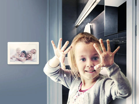Child with raised hands in front of a mounted hands free Z Wave gesture controller for smart homes, no touch swipe pad visible.