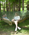Two people sitting in green Outdoor Camping Hammock With Mosquito Net And Bug Net Dope 13 Foot Parachute Nylon Hammock With Tree Straps And Carabiners