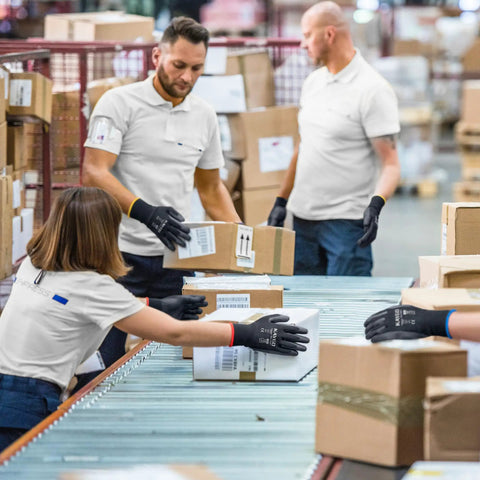 Workers wearing Lightweight Seamless Knit PU Coated Work Gloves for Men and Women with Smooth Palm Grip handling boxes.