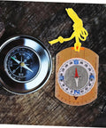 Trail Ready Orienteering Compass with Multi Function Built In Ruler Pointer And Luminous North next to metal compass on wood surface