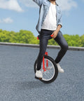Person riding 16 Inch Adjustable Unicycle For Outdoor Fitness And Fun, Rugged Ergonomic Design, red, on asphalt with blue sky