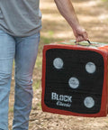 Classic Layered Foam Archery Target 22 Inch By 22 Inch Two Sided Shooting Target With Open Layer Design Stops Arrows With Friction Not Force Easy Arrow Removal Beefy Top Carry Handle being carried by a person in outdoor setting.