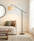 Tall Arc Floor Lamp With Sturdy Base In Rubbed Bronze LED Reading And Living Room Light Adjustable Arm For Dope Mid Century Modern Vibe Bedroom And Office Decor beside a sofa in a stylish living room.