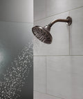 Five Setting Raincan Shower Head With H2Okinetic Spray in Venetian Bronze releasing water in modern bathroom with tiled wall