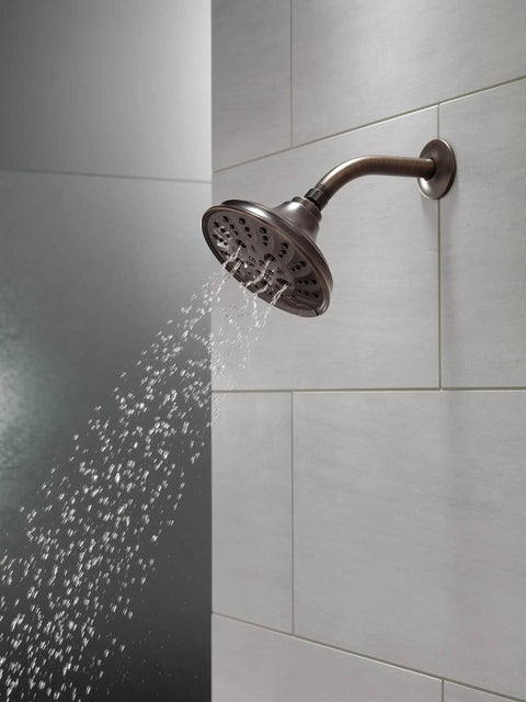 Five Setting Raincan Shower Head With H2Okinetic Spray in Venetian Bronze releasing water in modern bathroom with tiled wall