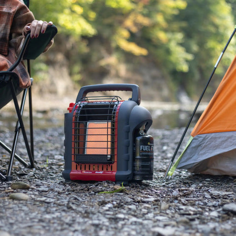 Portable Propane Heater With 9,000 BTU Radiant Heat for Indoor or Outdoor Use placed on rocky ground near camp tent.