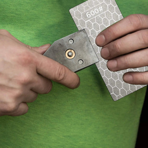 Person holding a 600 grit diamond plate honing stone for kitchen sharpening, part of the Four Pieces Diamond Sharpening Stone Grit Diamond Plate Honing Stone For Kitchen Sharpening Dull Edges Get Your Edge Back 5.9 By 2.48 Inches With 400 600 1000 And 1200 Grits set.