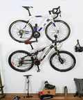 Wall Mounted Bike Pedal Hook Rack For Indoor Storage And Garage Organization With Tire Brackets Space Saving Hanger To Hold Three Bikes At A 45 Degree Angle No Handlebar Turning installed on white wall with two bikes mounted