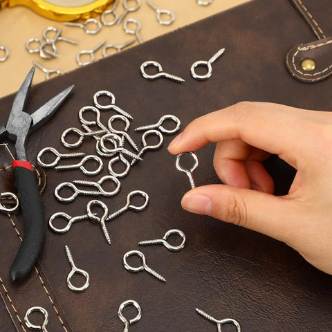 Hand holding Heavy Duty 1 Inch Eye Screws Hooks Set 150 Pack Screw Eyes For Wood Hanging Artwork Ropes And Light Loads Tough As Nails