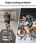Cyclist using an indoor bike roller trainer with parabolic rollers on foldable aluminum stand at home gym