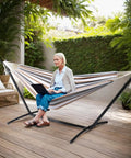 Person sitting on 550 Lb Capacity Double Hammock With Stand And Carry Bag For Outdoors And Indoors, Heavy Duty Two Person Hammock With 60x80 Inch Bed in patio.