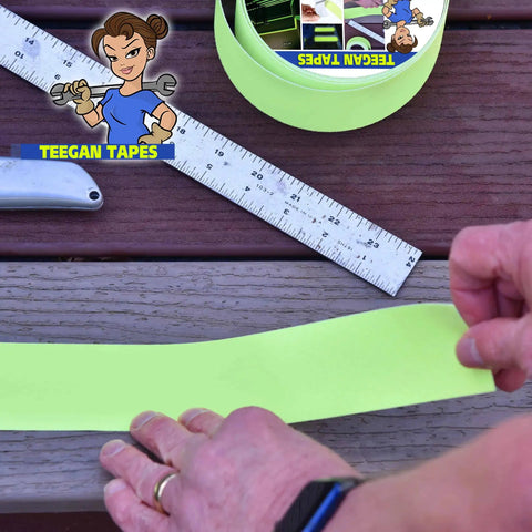 Hands applying Grippy Black Grip Tape For Stairs And Outdoor Use, Waterproof, Ultra Strong Adhesive, Clear Non Slip Stair Treads Tape, 4 Inch Wide By 30 Feet, Keeps Wet Walkways From Slipping with ruler on wooden steps
