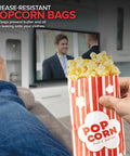 Person holding Large 2 Oz Red And White Paper Popcorn Bags Bulk 100 Pack Disposable Grease Resistant Bags watching TV