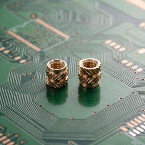 Premium 48Pcs Brass M4 Heat Set Threaded Inserts For 3D Printing placed on a green circuit board showcasing their knurled design.