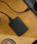 5TB Portable External Hard Drive with Ransomware Defense and Password Protection connected to laptop on wooden desk, USB 3.1/3.0 compatible.