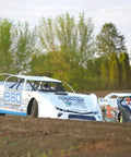 Race cars on dirt track in outdoor setting with trees in background