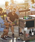 Outdoor gathering with 80 Quart Patio Cooler Cart With Blackboard, Bottle Opener And Drainage, includes drinks and bar tools.