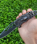 Close-up of Pocket Folding Knife With 3D Embossed Skull Pattern, 3.6 Inch Razor Sharp 440 Stainless Steel Blade in a hand.