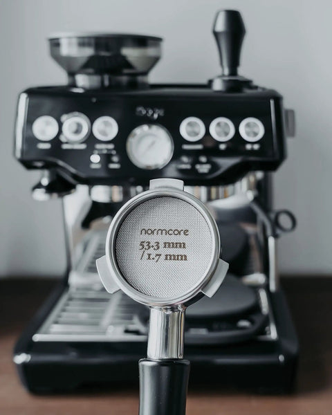 54mm Bottomless Naked Portafilter For Breville Barista Express And Barista Pro held in front of espresso machine