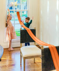 Kids playing with Flexible 15 Foot Race Car Track For Kids With Suction Cups Rolls Up Portable Racetrack super easy set up on chairs.