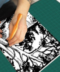 Person using Top Notch 5 Piece Linoleum Carving Tool Set featuring sharp triangular knife on artistic black and white design.