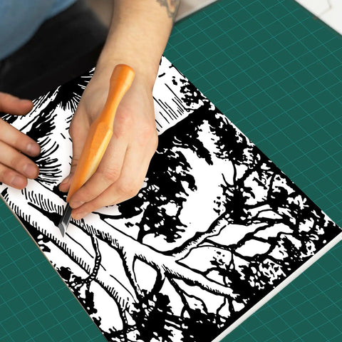 Person using Top Notch 5 Piece Linoleum Carving Tool Set featuring sharp triangular knife on artistic black and white design.