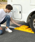 Person installing Ten Pack RV Camper Leveling Blocks With Interlocking Design Non Slip Pads under a travel trailer wheel.