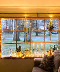 Bright 100 LED String Lights Indoor Outdoor 33 Ft With 8 Modes Warm White illuminating window with plants and candles
