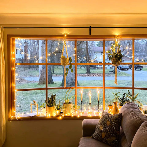 Bright 100 LED String Lights Indoor Outdoor 33 Ft With 8 Modes Warm White illuminating window with plants and candles