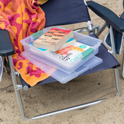 Stackable clear plastic storage bins with latching lids on a chair, used for organizing books, titled Six Pack Clip Boxes With Latching Lids.