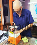 Adult using orange glass grinder in workshop with stained glass tools and materials.