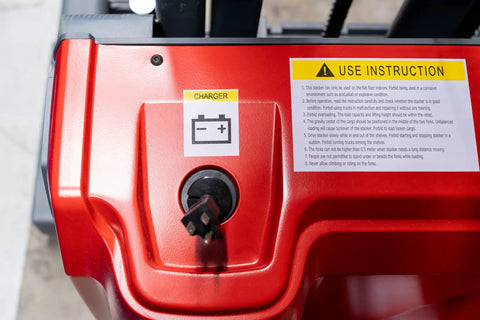 Close-up of Heavy Duty Fully Electric Adjustable Straddle Stacker charger port with warning sticker.
