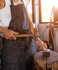 Steel bench block 30x50x10mm on anvil, front view of a person hammering in a workshop