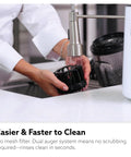 Hands rinsing Hurom H70 Cold Press Juicer components under faucet, demonstrating easy clean design.