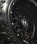H108 Sprocket 22X12 Road Beast Rim Delivers 8X170 Bolt Lugs And -44 Offset with asphalt satin black coating on tire.